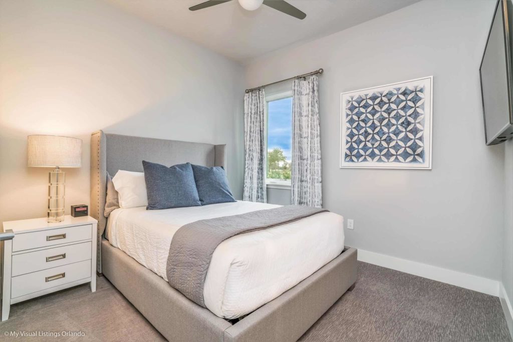 Furnished bedroom suite with TV, large closet doors, and window inside a Spectrum Resort Orlando vacation home rental.