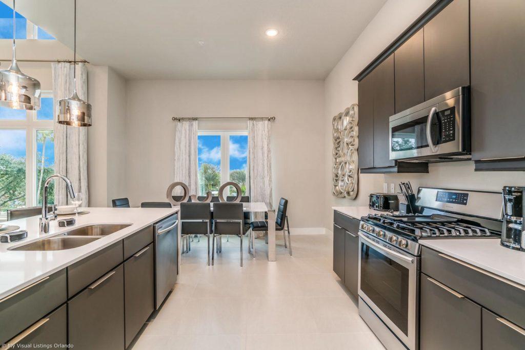 Furnished kitchen with island sink inside a Spectrum Resort Orlando vacation home rental.