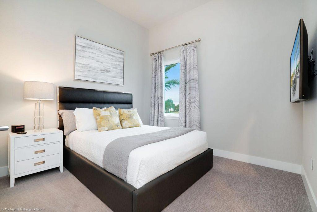 Dormitorio en suite amueblado con TV dentro de una casa de vacaciones en alquiler de Spectrum Resort Orlando.