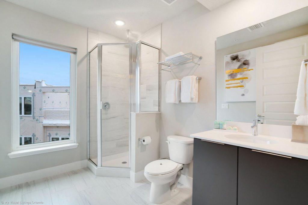 Baño amueblado con ducha de pie dentro de una casa de vacaciones en alquiler de Spectrum Resort Orlando.