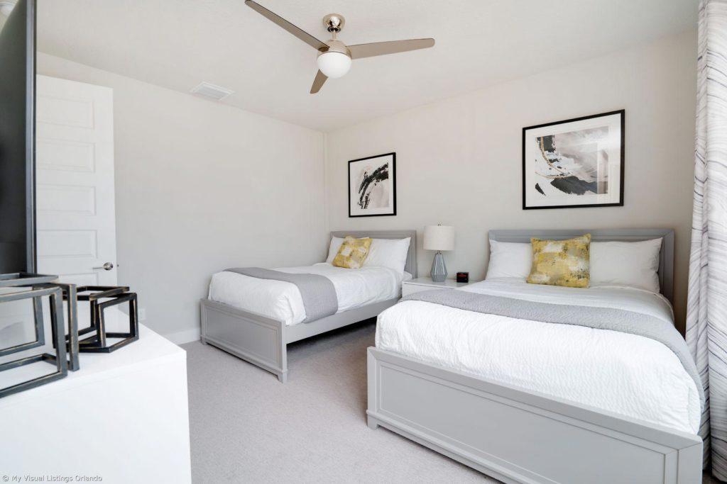 Dormitorio en suite amueblado con camas dobles completas dentro de una casa de vacaciones en alquiler de Spectrum Resort Orlando.