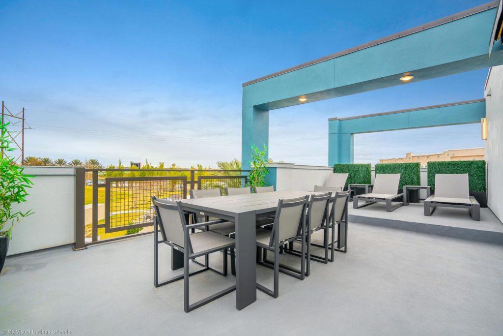 Balcón al aire libre en el nivel superior con iluminación, sillones y mesa de comedor en una casa de vacaciones en alquiler de Spectrum Resort Orlando.