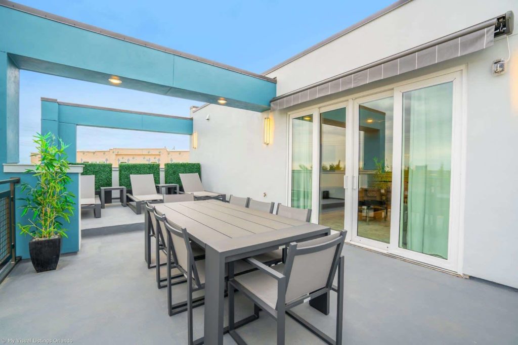 Balcón al aire libre en el nivel superior con iluminación, sillones y mesa de comedor en una casa de vacaciones en alquiler de Spectrum Resort Orlando.