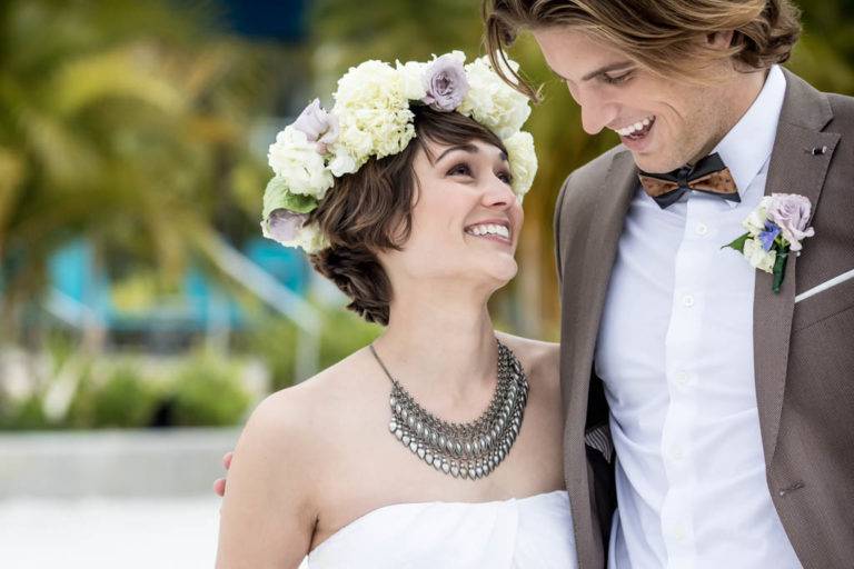 La novia y el novio se sonríen y caminan sobre la arena en Margaritaville Resort Orlando.