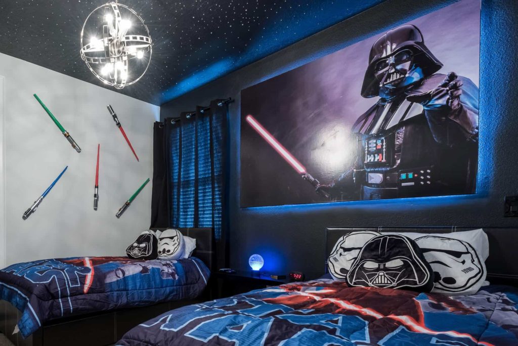 Star Wars-themed kids’ bedroom decorated with light sabers, posters, and bed sheets in an Encore Resort at Reunion residence.