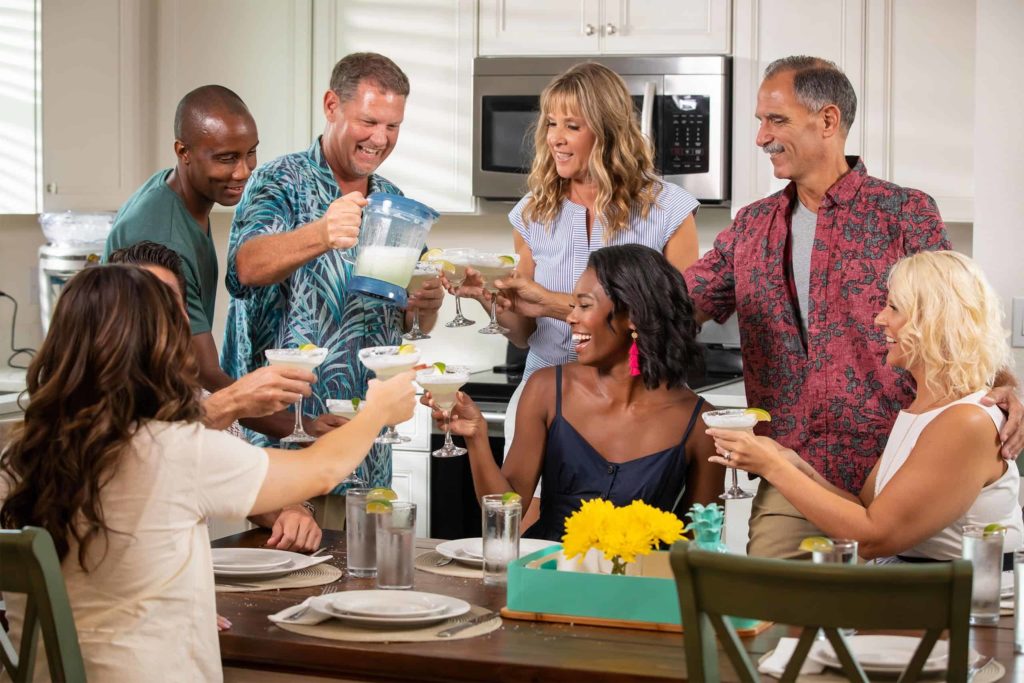 Paare, die mit Getränken in einer privaten Cottage-Küche des Margaritaville Resort Orlando anstoßen