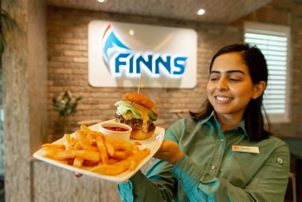 Finns Restaurant server holding a plate of a Finn burger and fries.