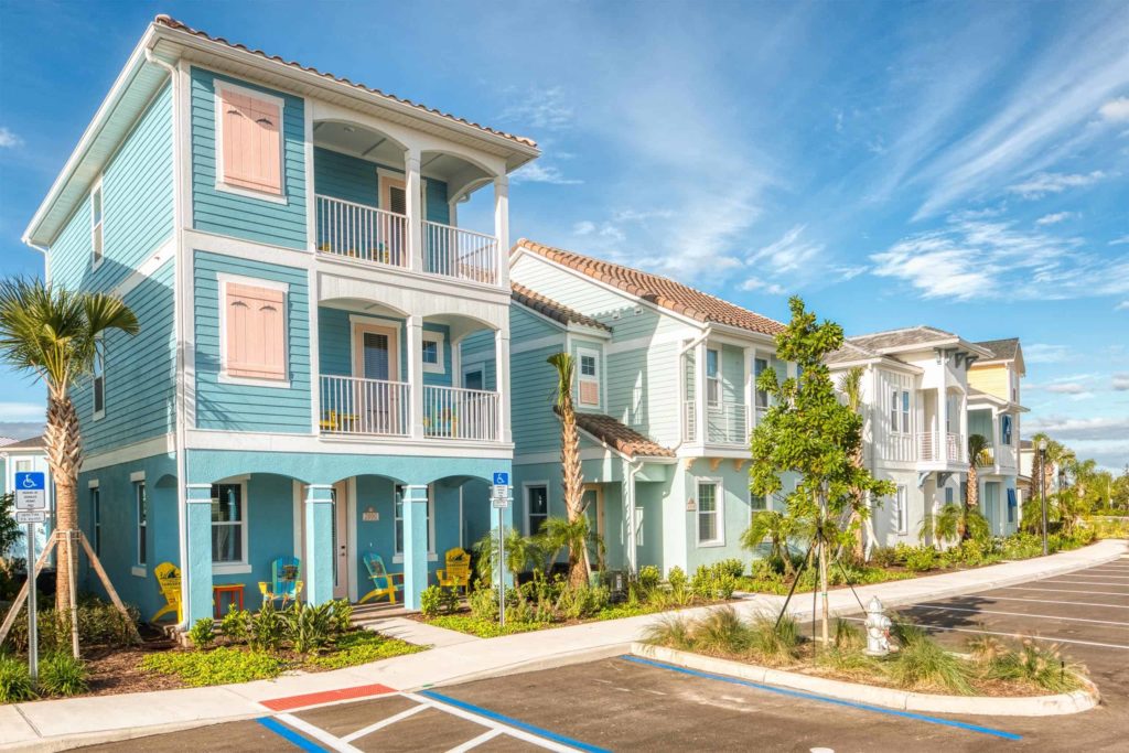 Reihe von farbenfrohen privaten Cottages im Margaritaville Resort Orlando mit Parkplätzen im Freien
