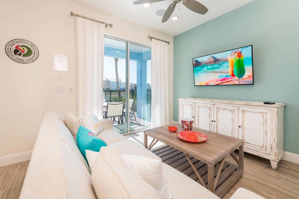 Sala de estar de la cabaña privada de Margaritaville Resort Orlando con TV montada en la pared y acceso al balcón