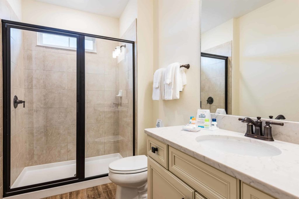 Baño de la cabaña privada de Margaritaville Resort Orlando con ducha a ras de suelo con puerta de vidrio