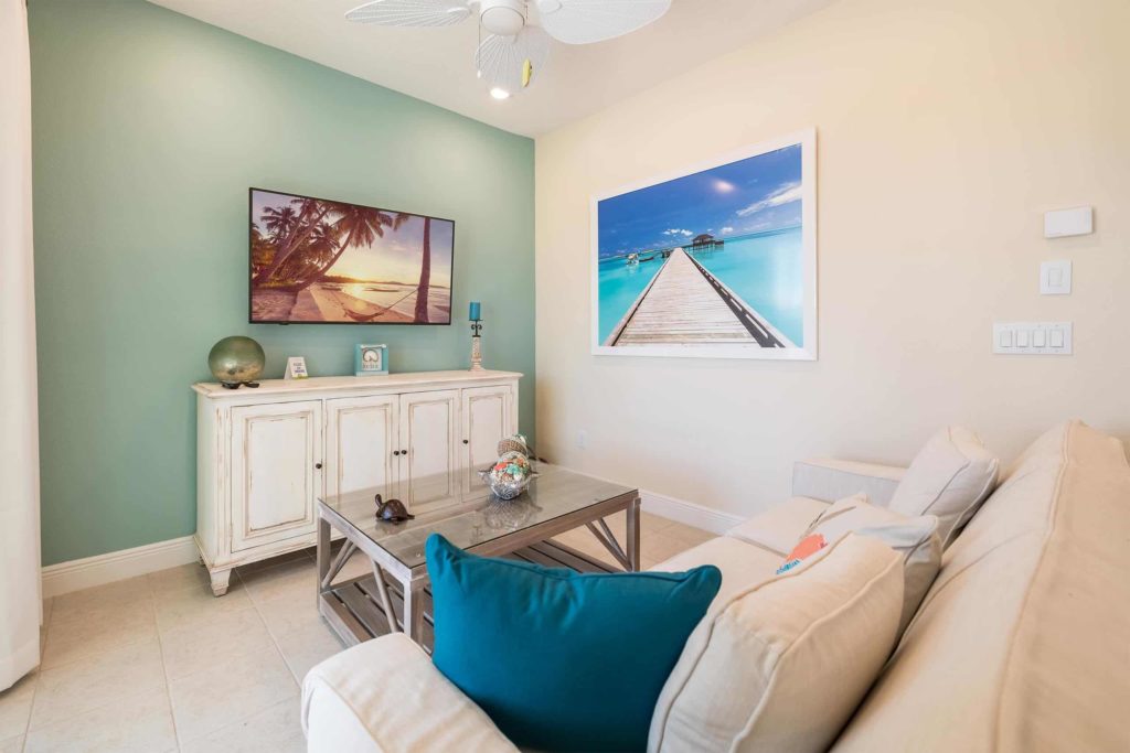 Sala de estar de la cabaña privada de Margaritaville Resort Orlando con arte tropical en la pared y TV montada en la pared