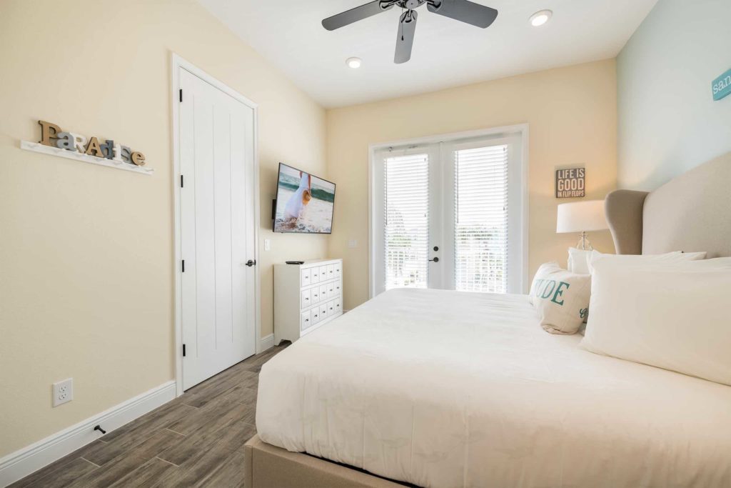 Margaritaville Resort Orlando privates Cottage-Schlafzimmer mit an der Wand montiertem Fernseher und Türen zum Balkon