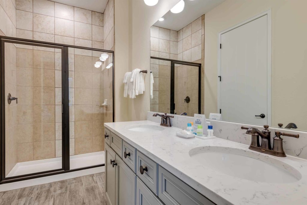 Baño de la cabaña privada de Margaritaville Resort Orlando con gran espejo de lavabo doble y ducha a ras de suelo