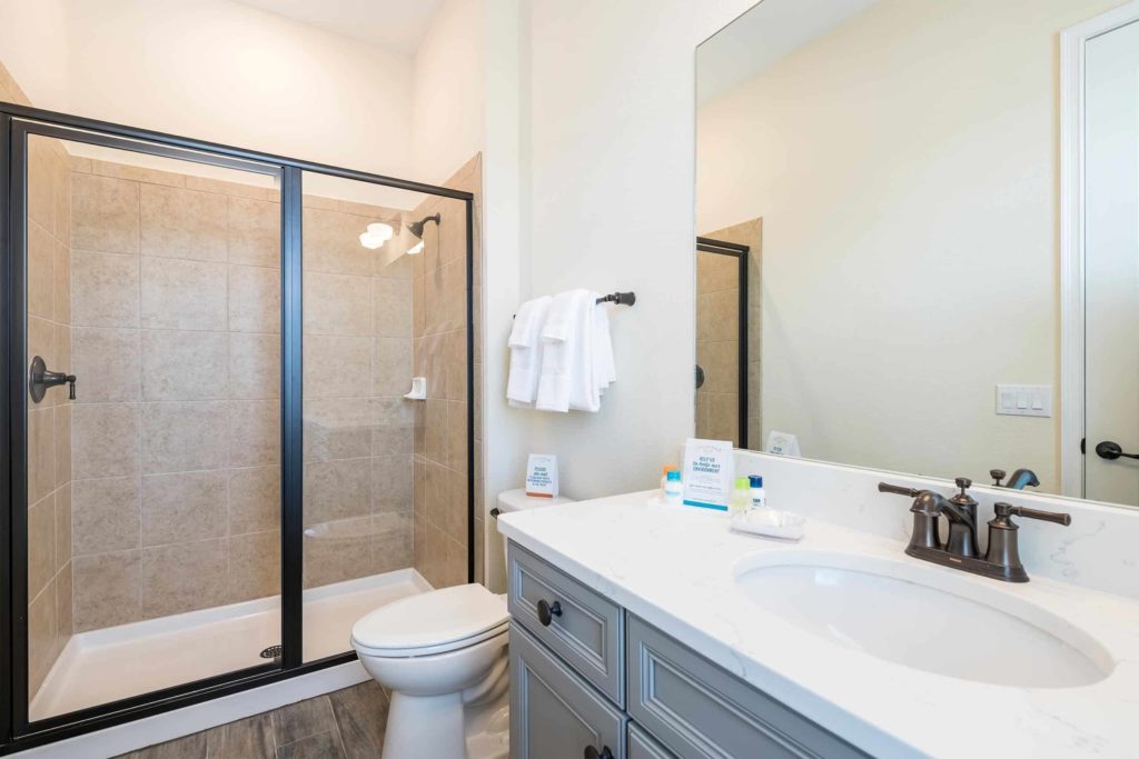 Baño de la cabaña privada de Margaritaville Resort Orlando con ducha a ras de suelo y espejo de lavabo grande