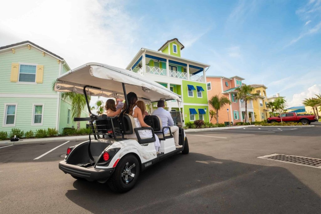 Familia llegando en carrito de golf a su casa de campo en Margaritaville Resort Orlando.