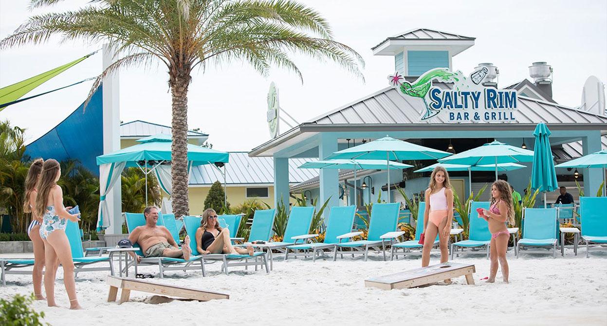 Family playing corn hole outside the Salty Rim Bar & Grill at Margaritaville Resort Orlando.