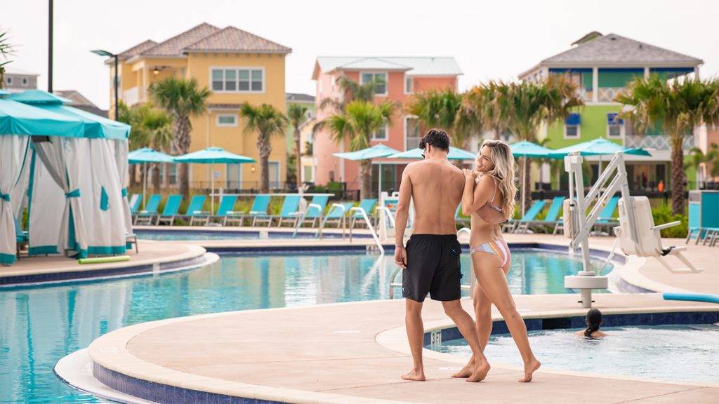 زوجان شابان يمشيان معًا بجوار مسبح Margaritaville Resort Orlando.