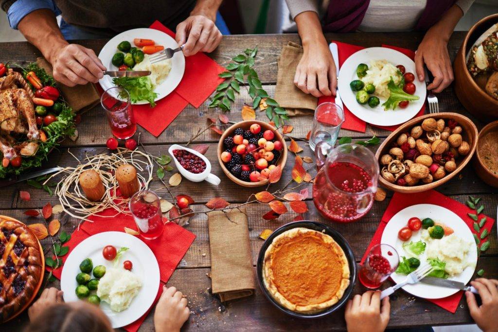 Family sitting around a table set for Thanksgiving dinner.