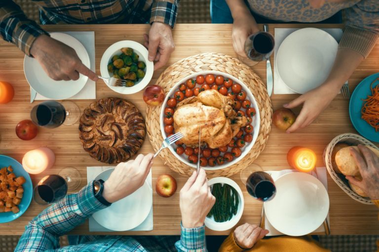 Family sitting around a table set for Thanksgiving dinner.