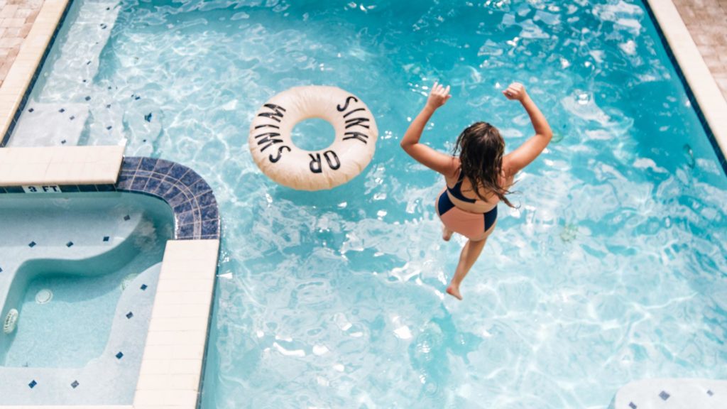 Woman jumping into a private pool at an Encore Resort vacation home rental.