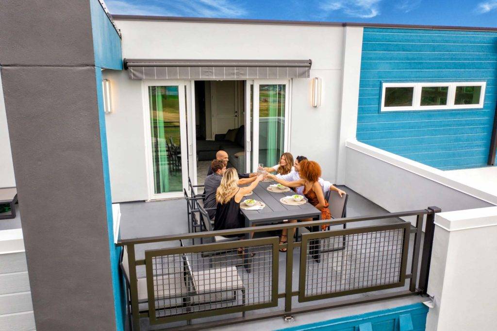 Familia sentada alrededor de una mesa en el balcón exterior de una residencia de Spectrum Resort Orlando.