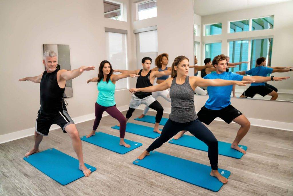 Grupo de personas haciendo posturas de yoga en el gimnasio Spectrum Resort Orlando.