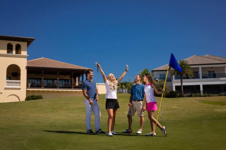 Mutter jubelt auf dem Golfplatz, umgeben von ihrem Partner und Freunden im The Bear's Den Resort Orlando.