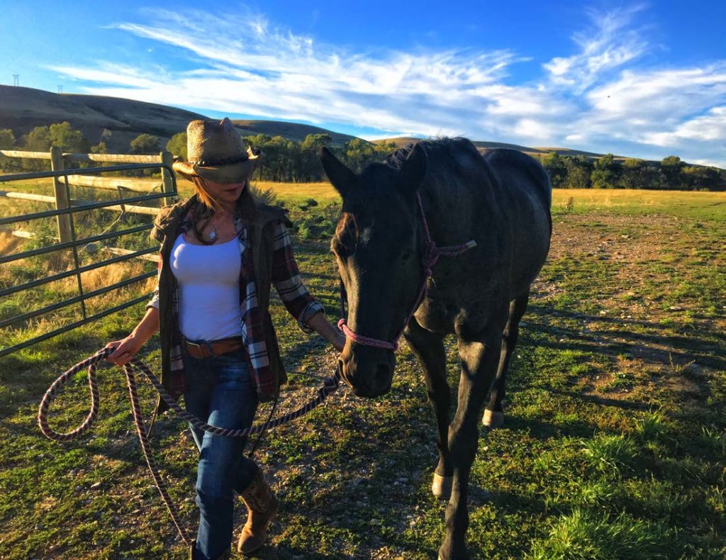 Woman leading a horse on a walk at The Ranches at Belt Creek’s Equestrian facility.