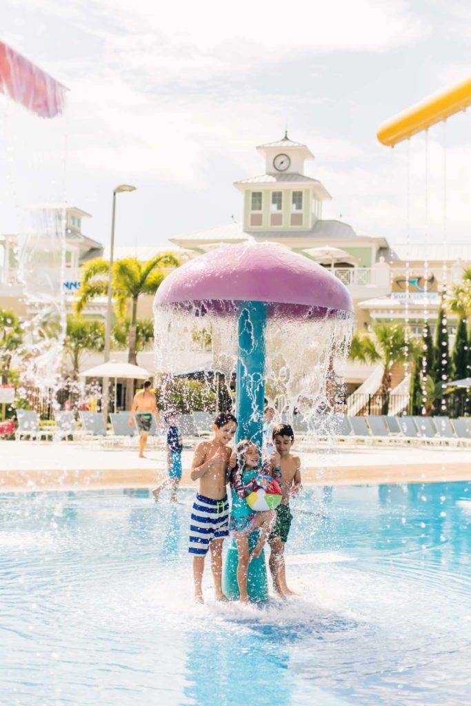 Kids playing under a mushroom fountain in the Encore Resort at Reunion water park’s splash area.