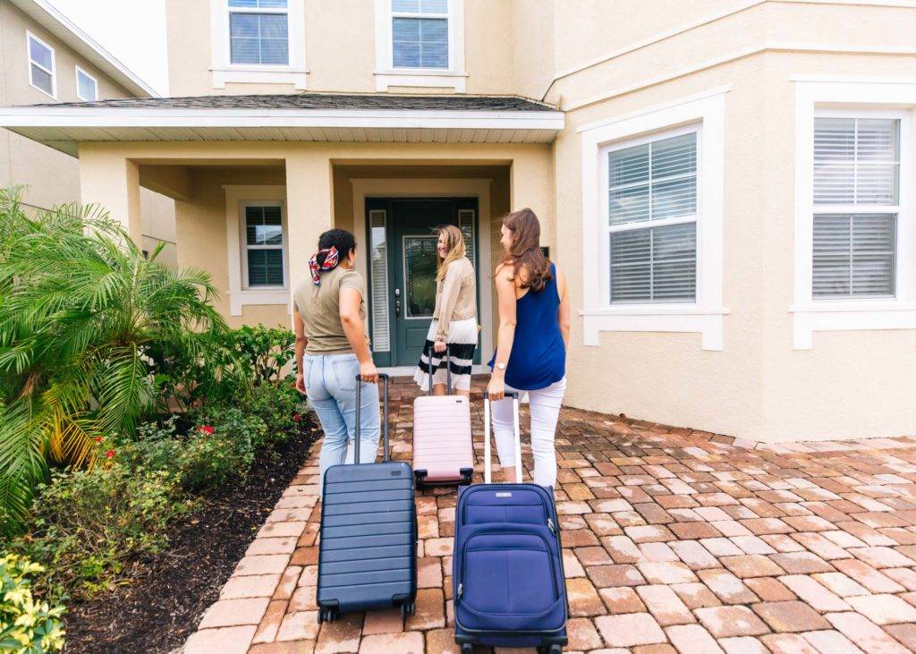 Three women happily arrive with luggage at their Encore Resort curated resort residence.