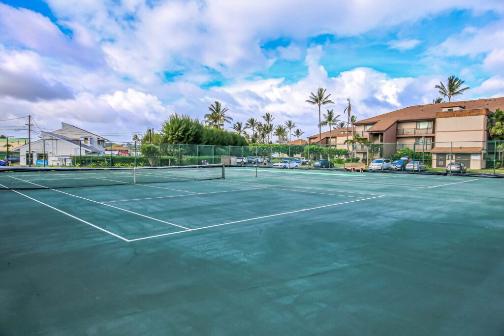 Cancha de tenis de tierra batida rodeada de palmeras en Pono Kai Resort.