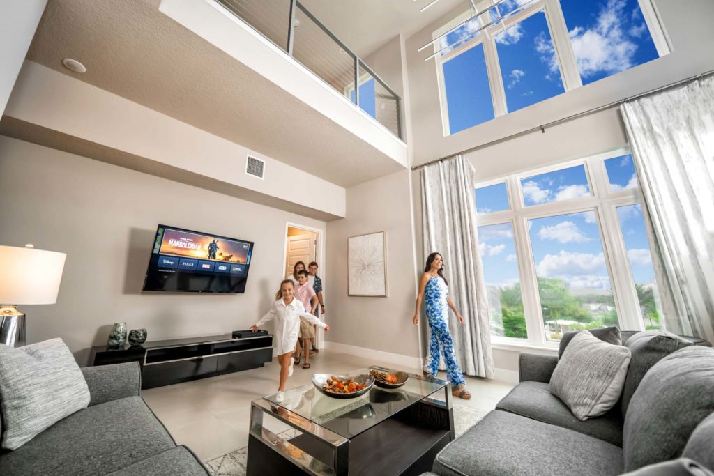Mamá e hijos entran a una espaciosa sala de estar en una residencia de Spectrum Resort Orlando.