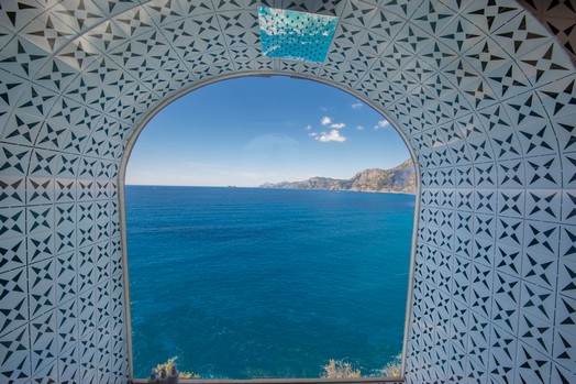 Ventana de mosaico de la casa de la piscina de Villa Lilly con vista al mar.