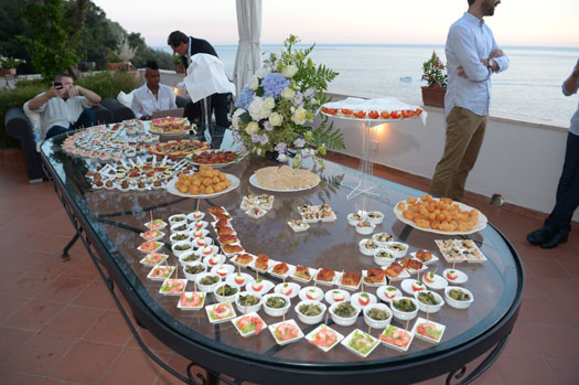 Hors d'ouvres alineados en una mesa larga en el balcón al aire libre de Villa Lilly durante un evento privado.