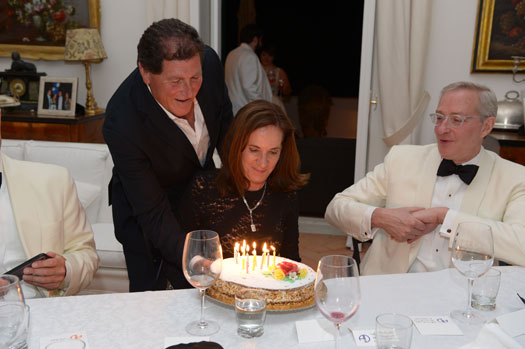 A Villa Lilly staff member presents a cake with lit candles to a guest during a private event.