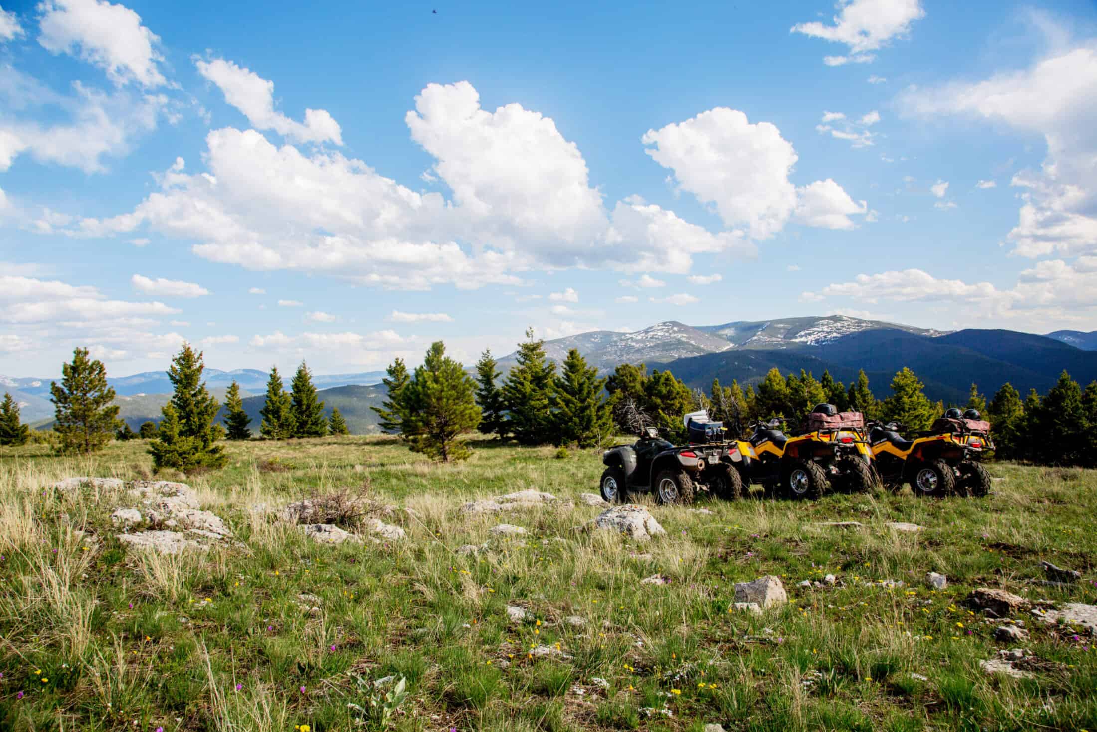 Cuatrimotos en fila en una colina con vista a las montañas en The Ranches at Belt Creek.