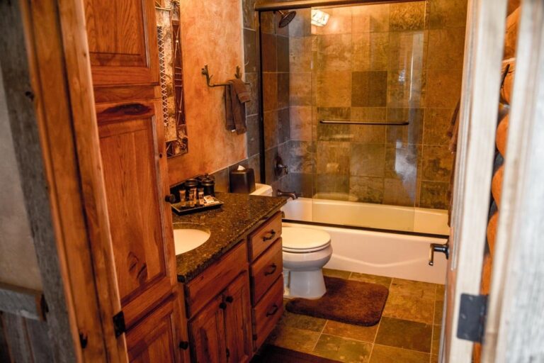 Lazy Doe Ranch rustic bathroom with glass door bathtub/shower combo.