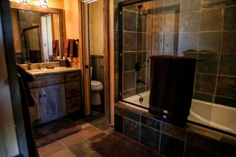 Bathroom with glass door bathtub/shower combo at The Ranches at Belt Creek member cabins.