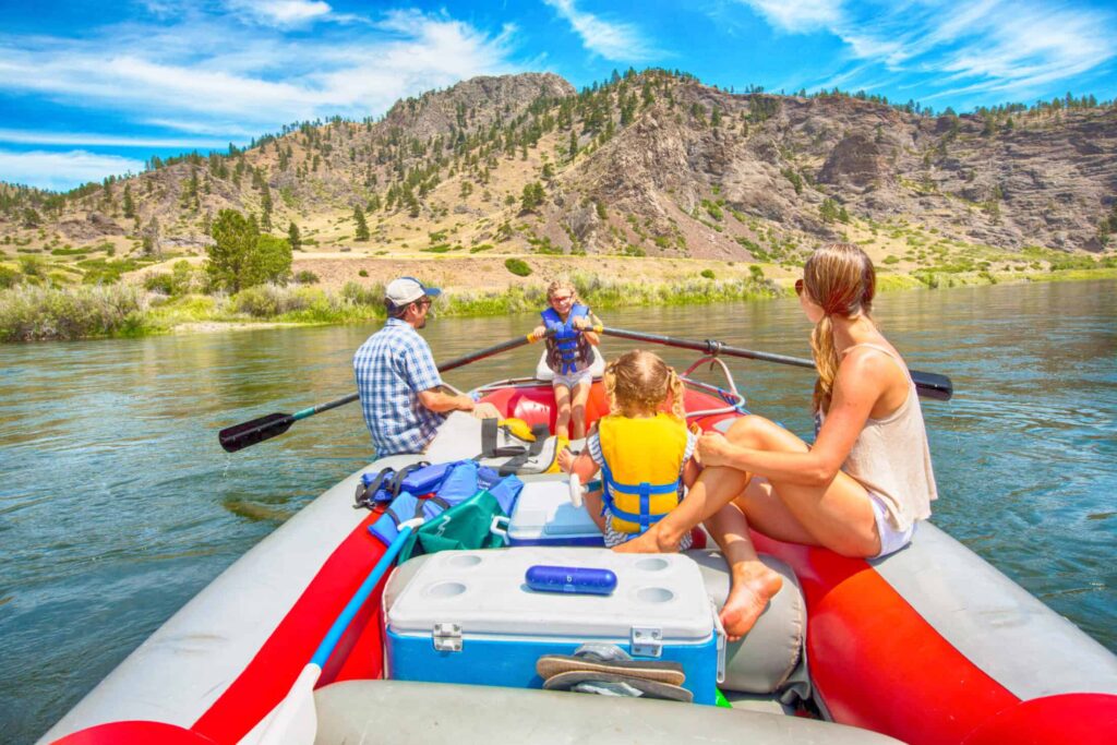 Niña remando una balsa de río con su familia en Belt Creek, Montana.