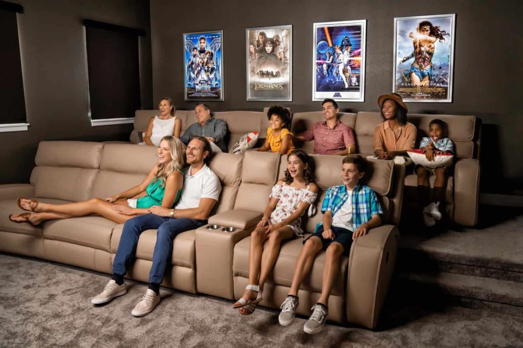 Familia numerosa de abuelos, padres e hijos felices viendo una película en una sala de cine de Bear's Den Resort Orlando.