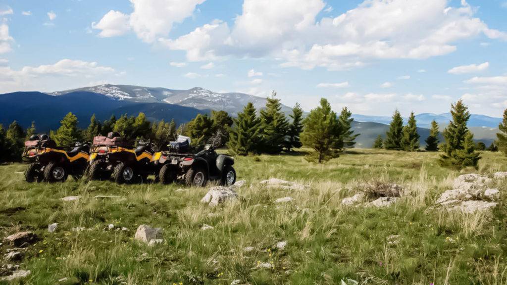 Outdoor-Aktivitäten Reihe von ATVs, die vor einer malerischen Bergkulisse bei The Ranches at Belt Creek geparkt sind.
