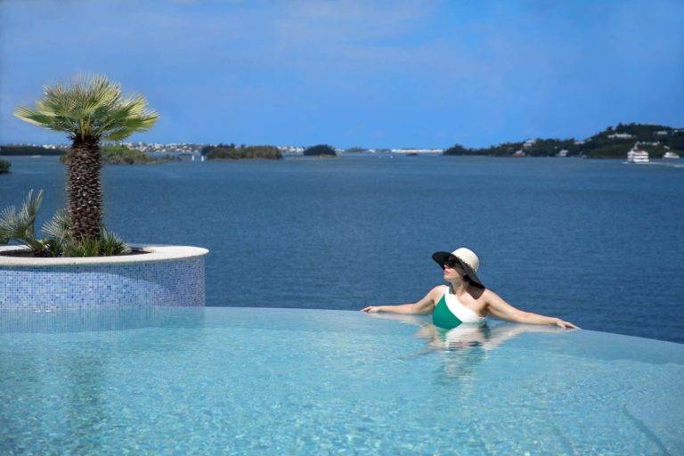 Mujer en las Bermudas en la piscina infinita del resort Newstead Belmont Hills con vista al agua.
