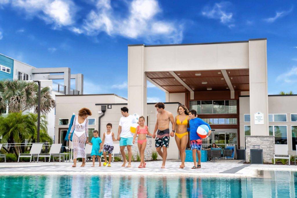 Familia caminando de la mano hacia la piscina de la casa club en Spectrum Resort Orlando.