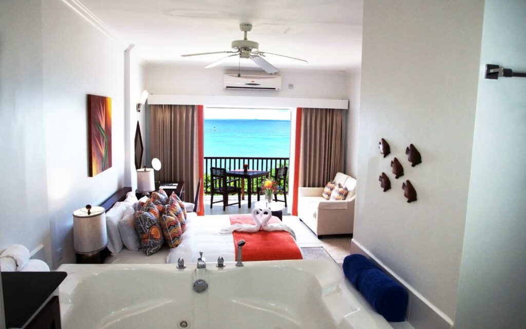 Sunset Ocean View Junior Suite with king bed, Jacuzzi, and ocean view balcony.