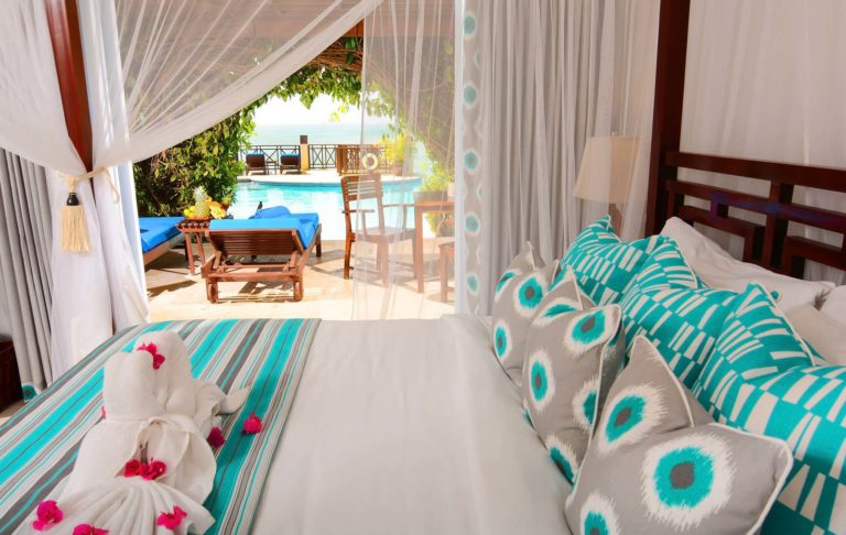 Four poster bed in a swim-up Jr. Suite at Calabash Cove with direct pool access and a large patio.