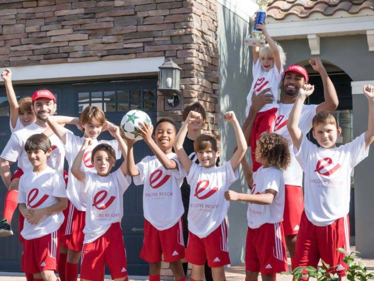 Sports team of kids and their coaches in matching Encore Resort at Reunion T-shirts cheering outside their resort residence.