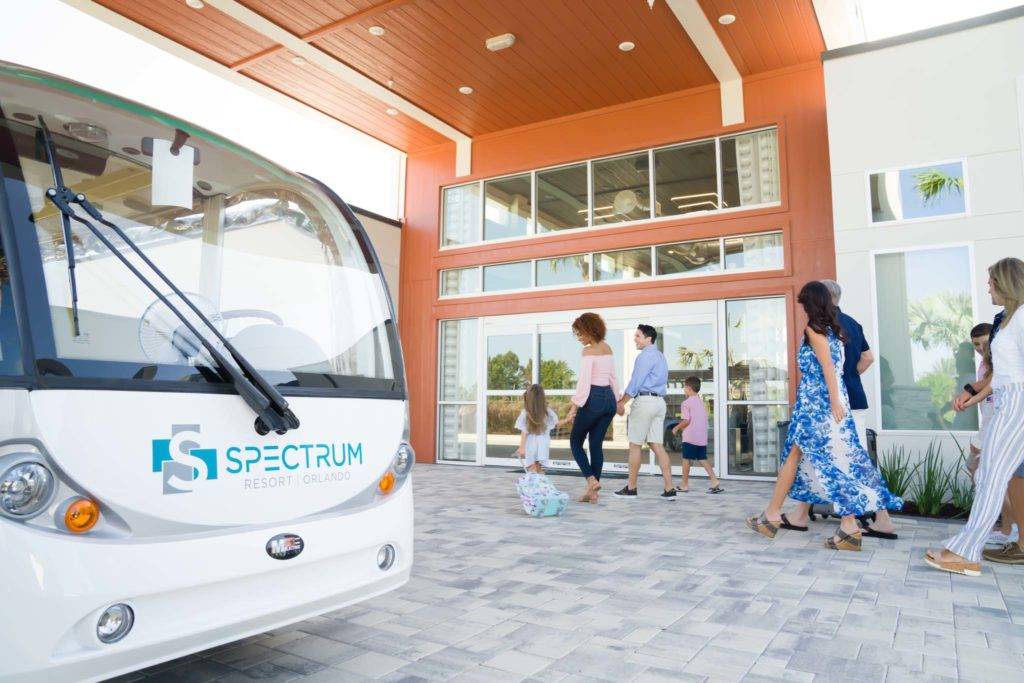 A Spectrum Resort Orlando shuttle drops off a happy family at the resort clubhouse entrance.