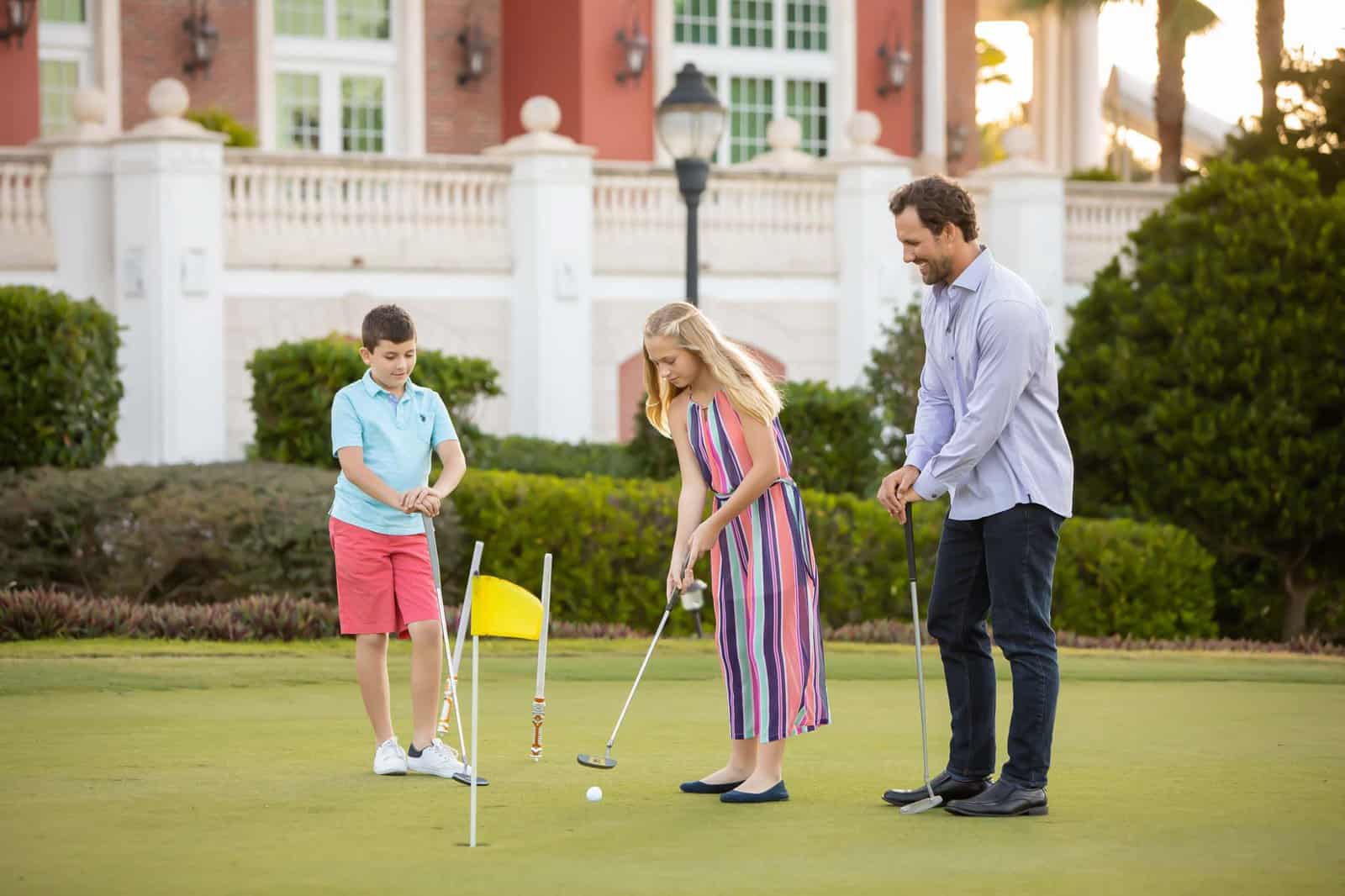 Dad With His Children On A Golf Course Putting Green.