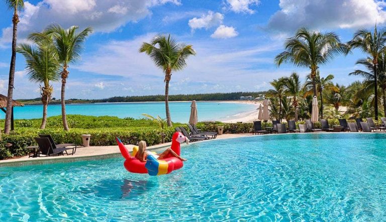 Woman Relaxing In A Colorful Float In An Infinity Pool Overlooking Grand Isle Resort’s Beach.