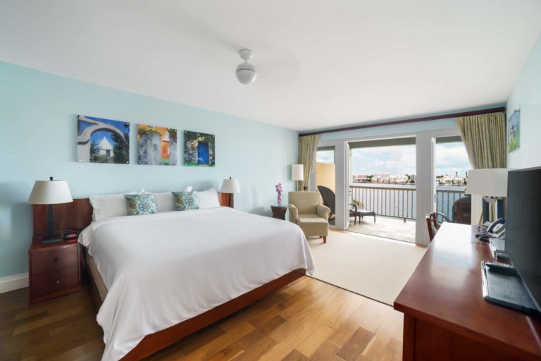 Dormitorio en suite con cama King grande y balcón privado en Rentyl Resorts.